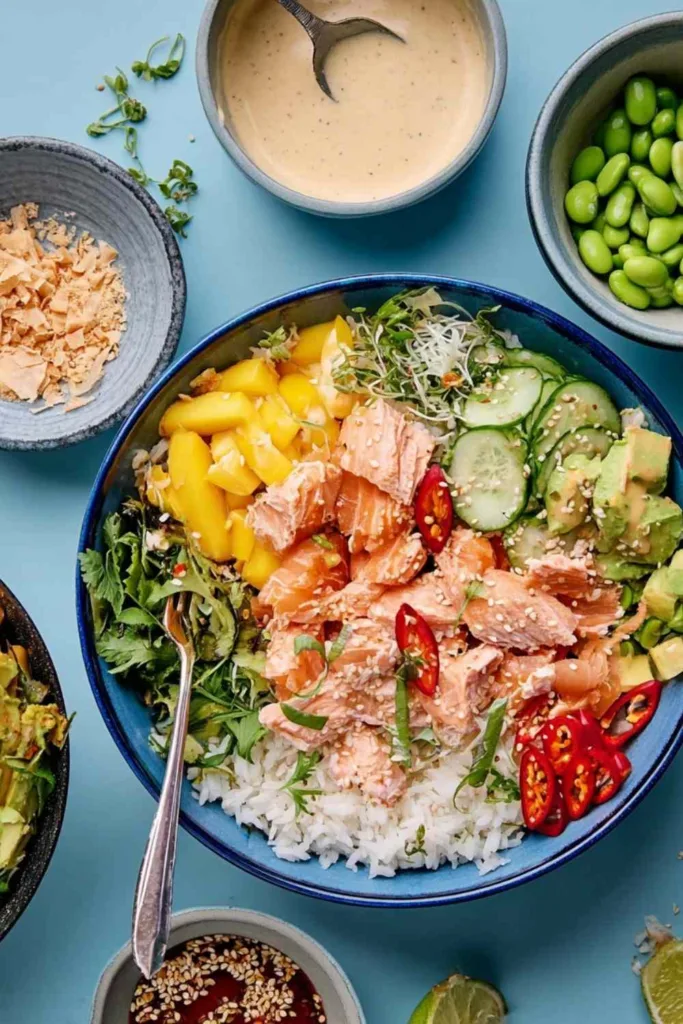 Coconut rice salmon bowl topped with mango, avocado, edamame, cucumber, and coconut lime dressing