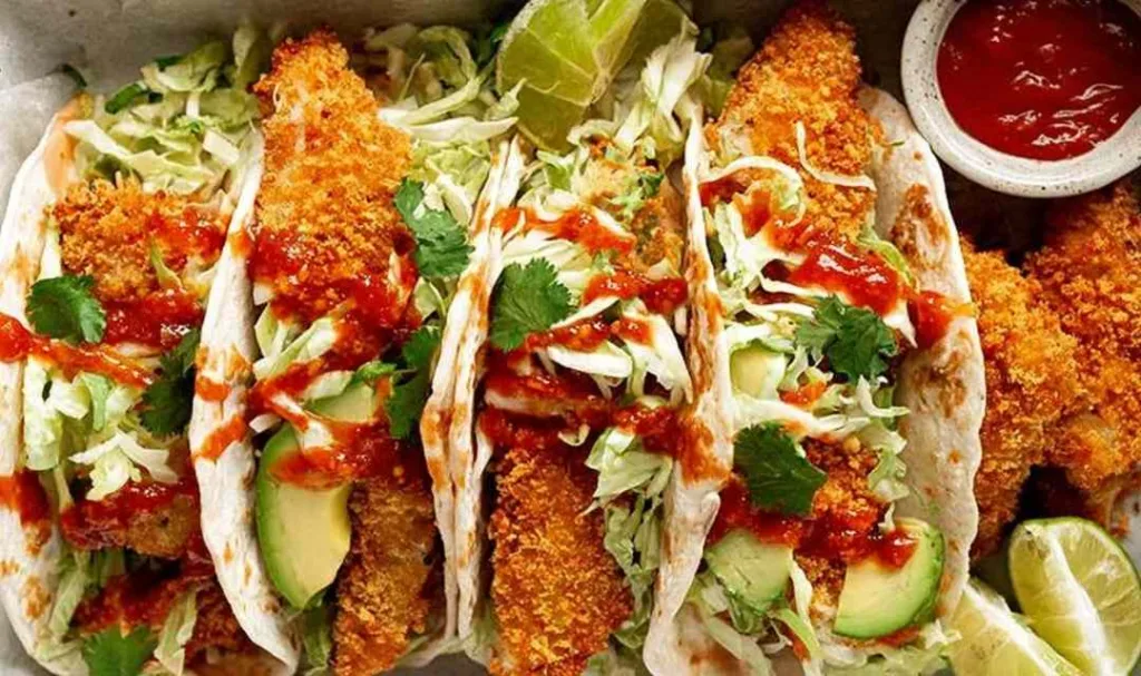 crunchy baked chicken taco fingers on warm flour tortillas with avocado slaw and sriracha
