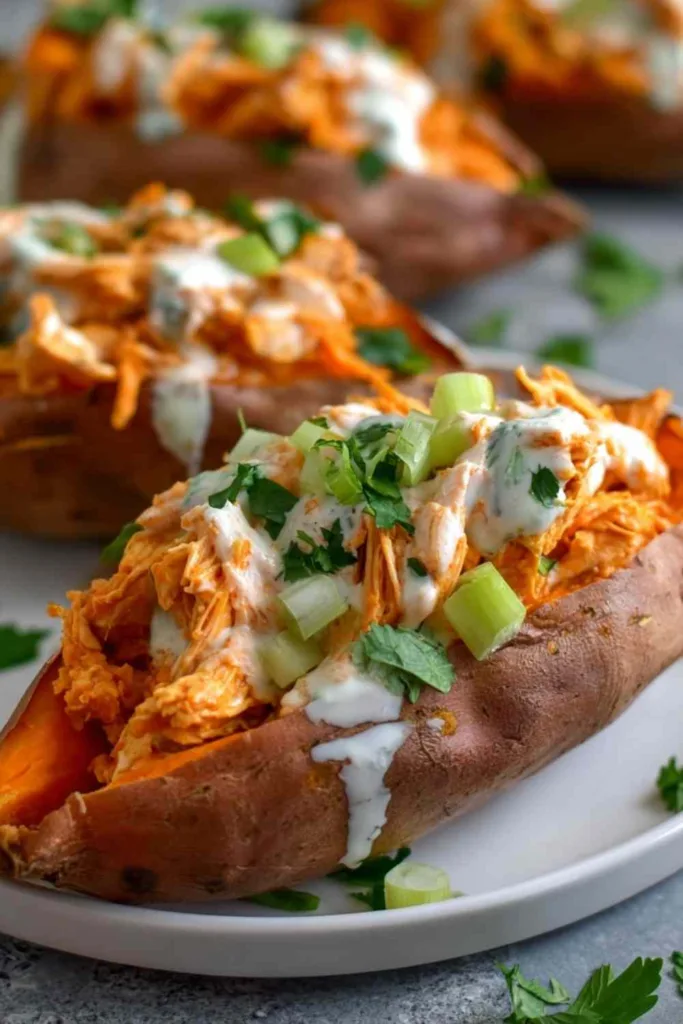 Overhead view of four buffalo chicken stuffed sweet potatoes drizzled with skinny blue cheese sauce on a lined baking sheet
