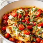 Caprese Chicken Skillet with golden seared chicken, melted mozzarella pearls, fresh tomatoes, and balsamic glaze in a cast iron skillet topped with fresh basil