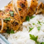 Four airtight meal prep containers filled with sliced chicken and rice meal prep bowls and steamed green beans