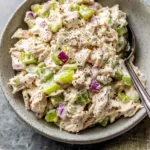 Classic chicken salad recipe served in a white bowl with celery and red onion