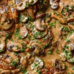 Creamy mushroom garlic chicken thighs in a cast iron skillet garnished with fresh parsley