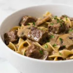 Crock pot beef stroganoff with tender beef and mushrooms in a rich creamy sauce inside a slow cooker