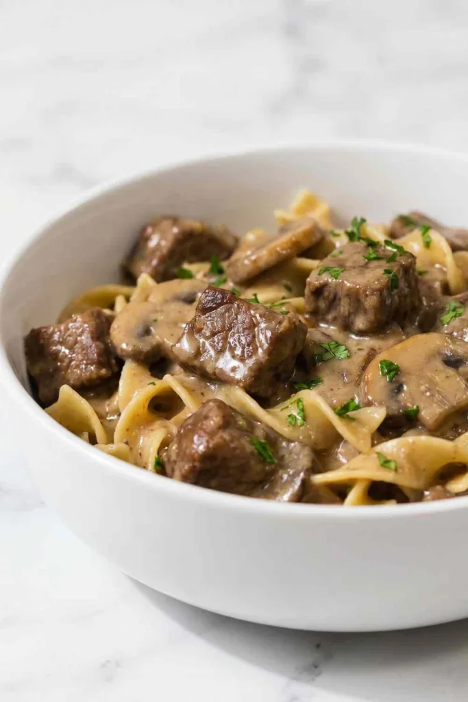 Crock pot beef stroganoff with tender beef and mushrooms in a rich creamy sauce inside a slow cooker
