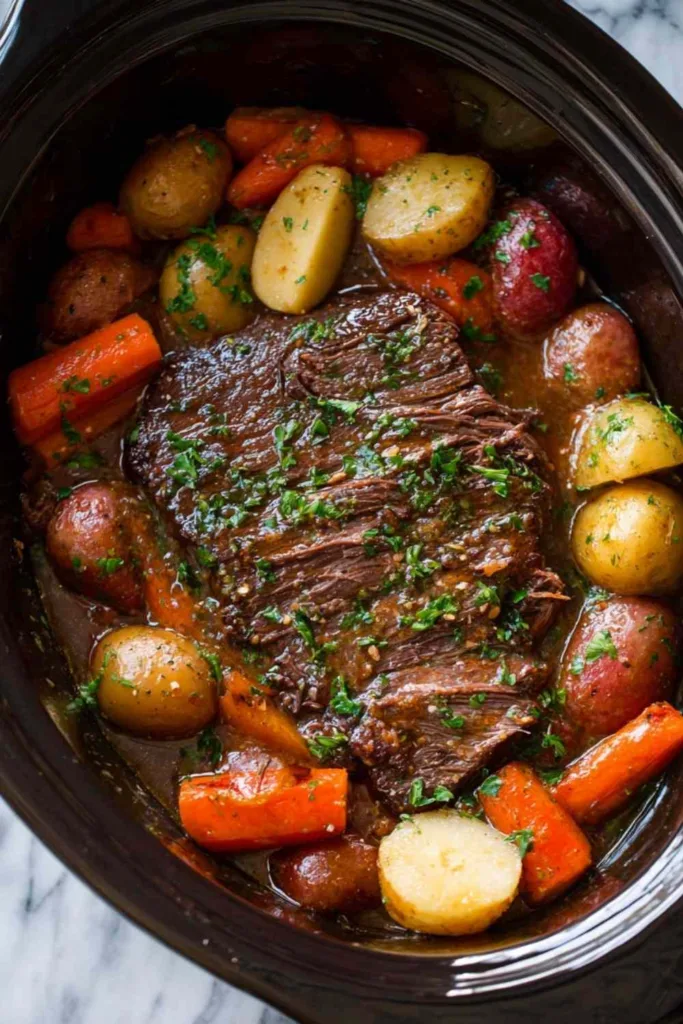 Tender crock pot roast with potatoes and carrots in a white slow cooker garnished with fresh parsley