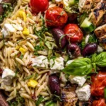 Greek Chicken Orzo Salad with grilled pesto chicken, feta, cherry tomatoes, and kalamata olives in a large serving bowl
