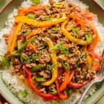 Ground chicken stir fry bowls served over jasmine rice with colorful bell peppers, green onions, and sesame seeds