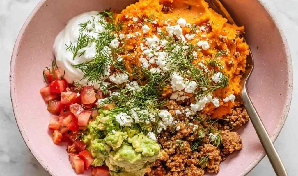 Ground turkey sweet potato bowl topped with guacamole pico de gallo sour cream and queso fresco