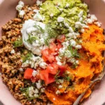 Ground turkey sweet potato bowl topped with guacamole pico de gallo sour cream and queso fresco