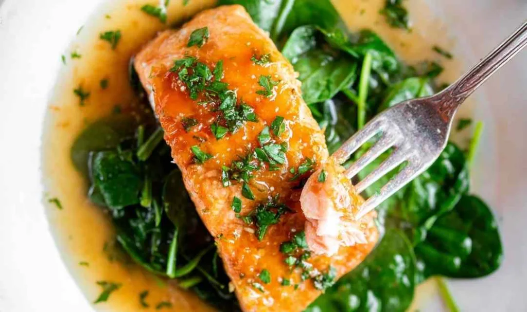 Honey garlic salmon baked in foil with shiny soy and garlic glaze on three skin-on fillets in a baking dish