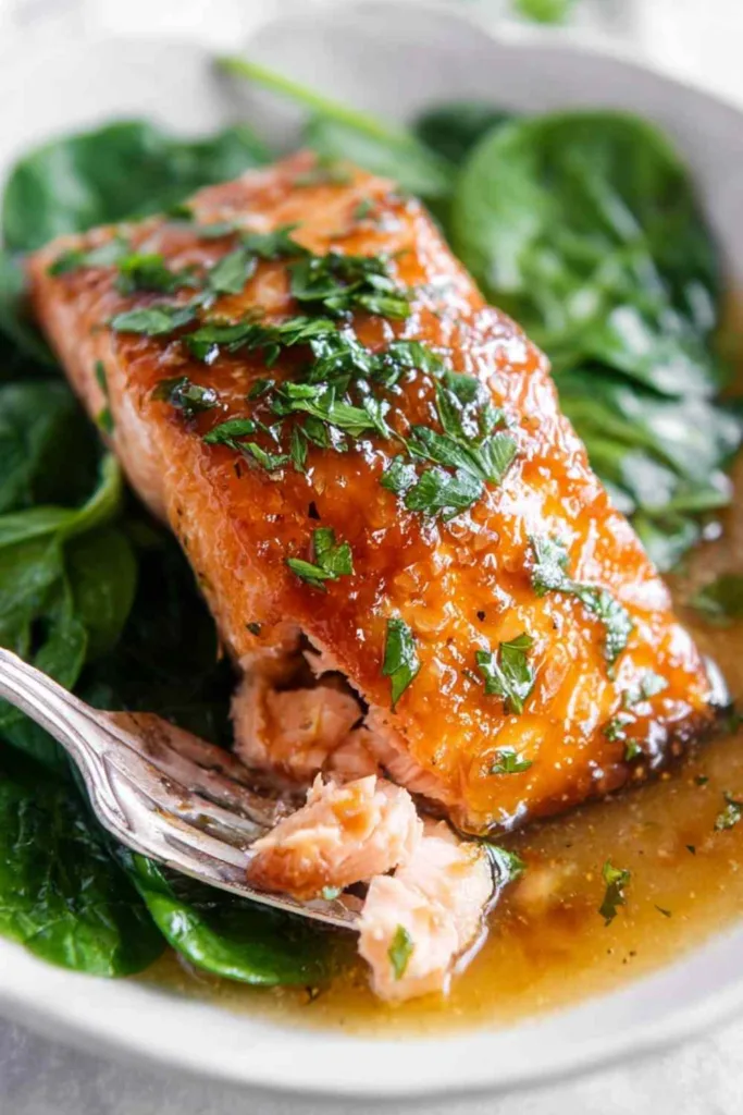 Honey garlic salmon baked in foil with shiny soy and garlic glaze on three skin-on fillets in a baking dish