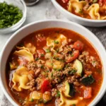 A warm bowl of sausage tortellini soup topped with shredded Parmesan and fresh parsley