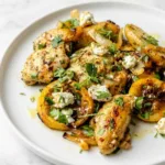 Sheet pan lemon chicken and potatoes topped with crumbled feta, fresh dill, and parsley on a large baking sheet