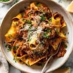 A bowl of slow cooked shredded beef ragu pasta topped with freshly grated Parmesan and chopped parsley