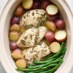 Slow cooker garlic butter chicken and potatoes with tender green beans in a white crockpot