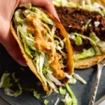 smash burger tacos on a plate topped with melted cheddar shredded lettuce and burger sauce
