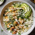 Street Corn Chicken Rice Bowl topped with charred corn, avocado, cotija cheese, and cilantro served family-style