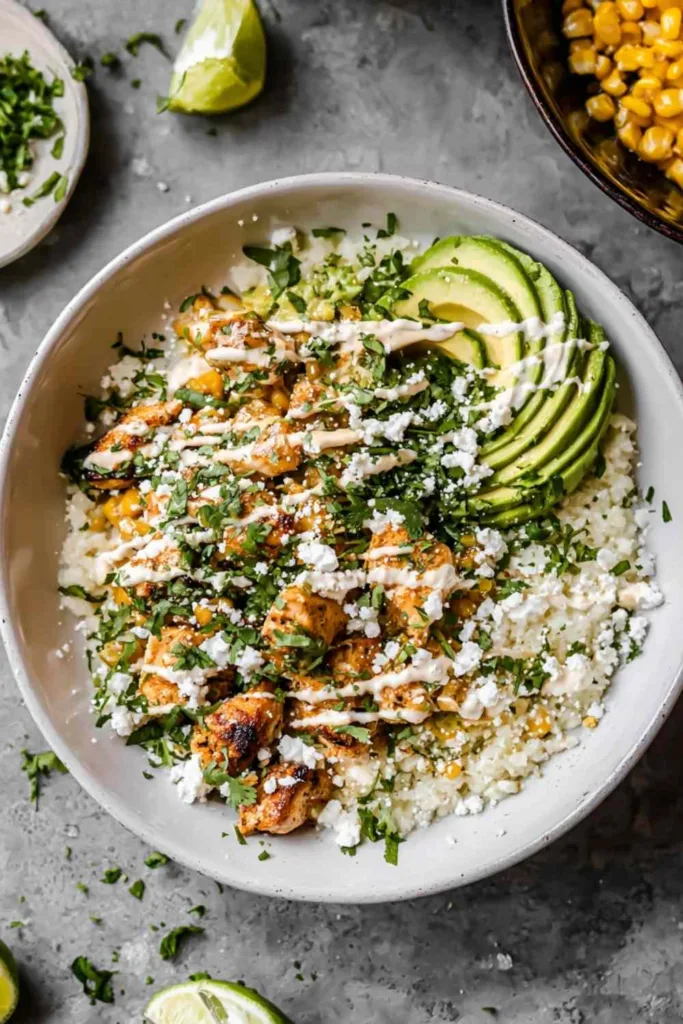 Street Corn Chicken Rice Bowl topped with charred corn, avocado, cotija cheese, and cilantro served family-style