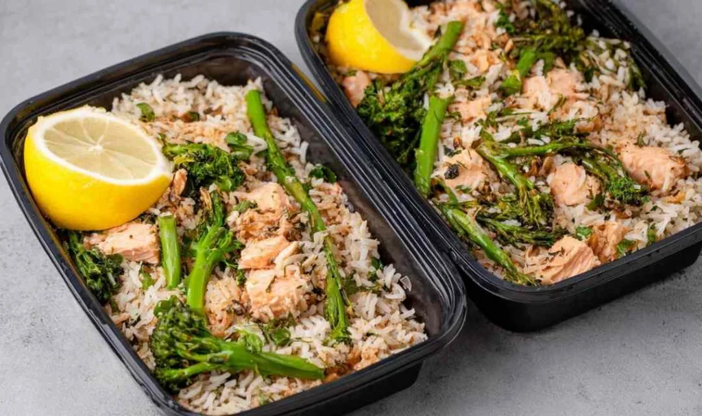 High protein salmon rice bowl with flaky salmon, jasmine rice, and asparagus in a meal prep container