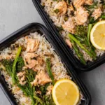 High protein salmon rice bowl with flaky salmon, jasmine rice, and asparagus in a meal prep container